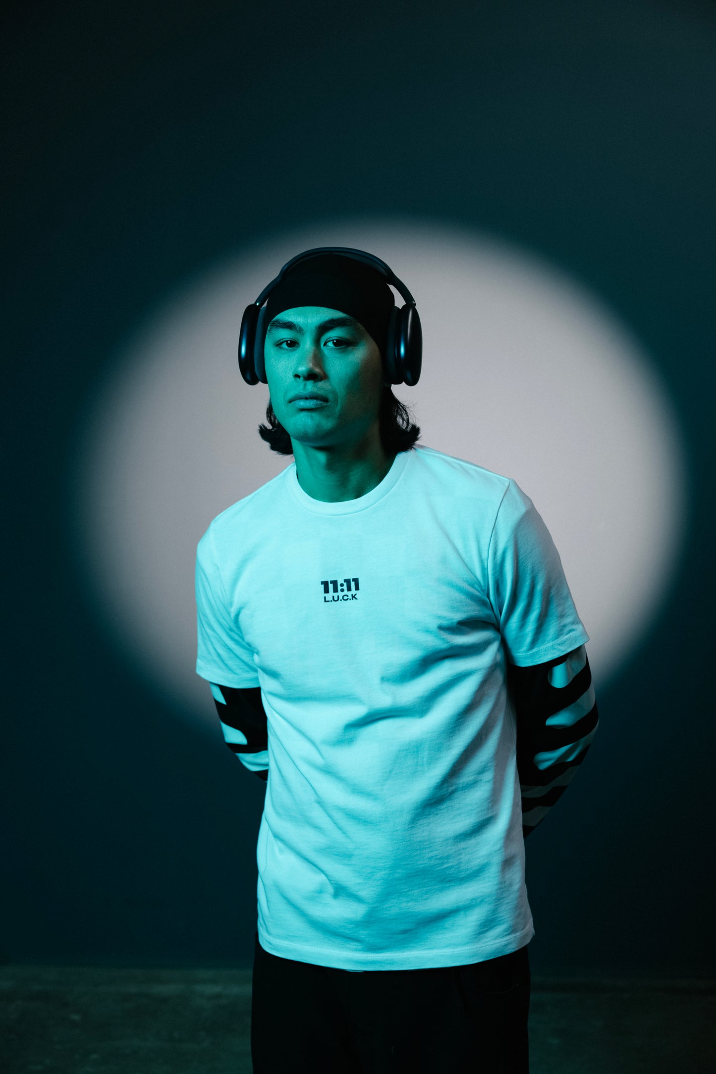 A model wearing a 11:11 L.U.C.K. shirt, sitting in a minimalistic setting, reflecting the brand’s message of empathy and mental well-being